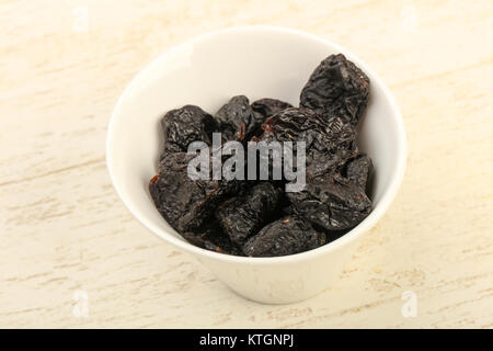 Dried plums heap in the bowl over wooden background Stock Photo