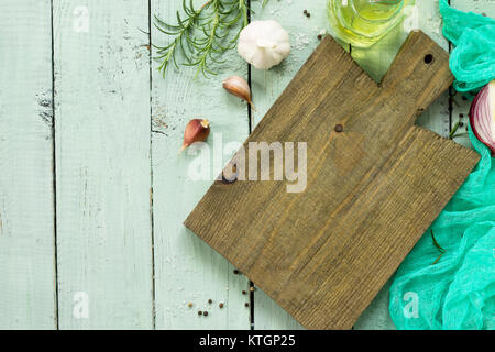 Empty cutting board on a wooden culinary background, various spices and rosemary. Flat lay, top view with copy space. Stock Photo