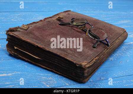 Glasses on the closed Bible on a blue wooden background. Stock Photo