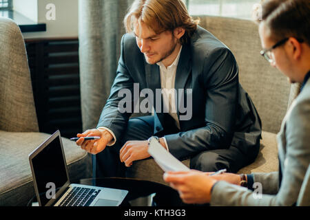 Two male employees consulting with laptop in cafe Stock Photo