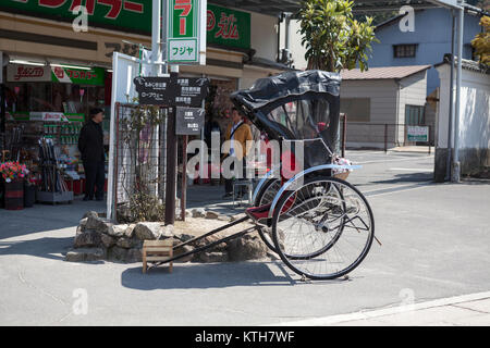 ITSUKUSHIMA, JAPAN-CIRCA APR, 2013: Rickshaw a two-wheeled passenger cart is on roads of Miyajima. Pulled rickshaw is a famous form of transportation  Stock Photo