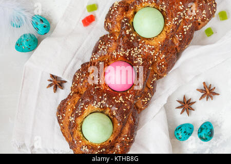 Traditional Greek Easter bread - tsoureki in Easter decorations with painted eggs and flowers. Easter Festival concept. Stock Photo