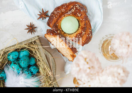 Traditional Greek Easter bread - tsoureki, sliced in Easter decorations with painted blue quail eggs in the nest and flowers. Easter Festival concept. Stock Photo