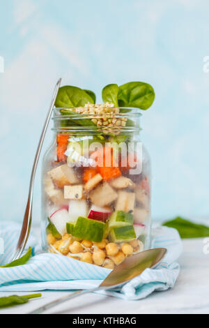 Warm tofu sweet potato salad in a jar, snack takeaway. Tofu, chickpeas and buckwheat sprouts, sweet potato, radish, spinach and cucumber. Vegan Health Stock Photo