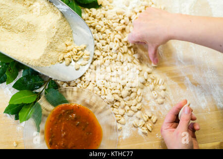 Woman making and preparing pisarei gnocchi typical pasta from Emilia Romagna, Piacenza, Italy at the restaurant kitchen preparation Stock Photo