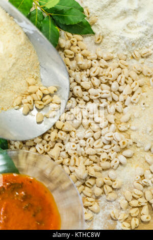Pisarei gnocchi pasta just made over a wooden table with dough, flour and spices. Shoot in Piacenza , Italy.  Then add tomato sauce and beans. ( faso Stock Photo