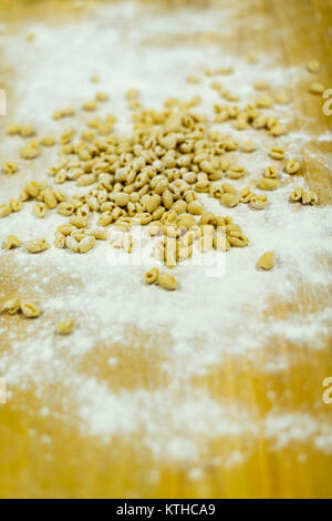 Pisarei gnocchi pasta just made over a wooden table with dough, flour and spices. Shoot in Piacenza , Italy.  Then add tomato sauce and beans. ( faso Stock Photo