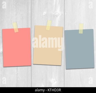 Three colored adhesive paper on a white wooden background. Stock Photo