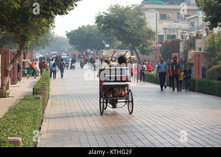 Cycle rickshaw with passengers going towards Shilpgram from Taj Mahal on Taj East Gate Road in Agra. Tourists going towards Taj Mahal are also visible. Stock Photo