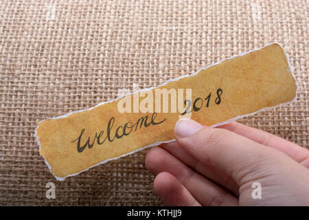 Welcome 2018 wording written on a torn paper in hand Stock Photo