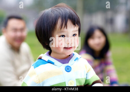 young asian parents with little girl outdoor in the lawn Stock Photo