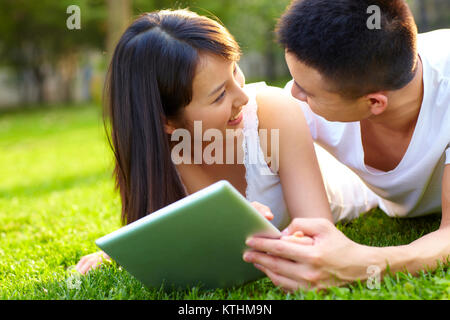 Young Chinese lover using table on lawn outdoor in the park Stock Photo