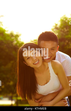 Young Chinese lover holding together in the park smile at camera in the beautiful summer light Stock Photo