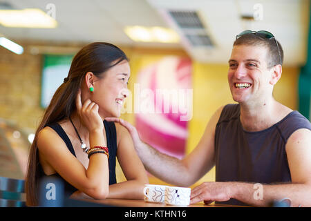 happy asian girl talking with white man in the cafe Stock Photo