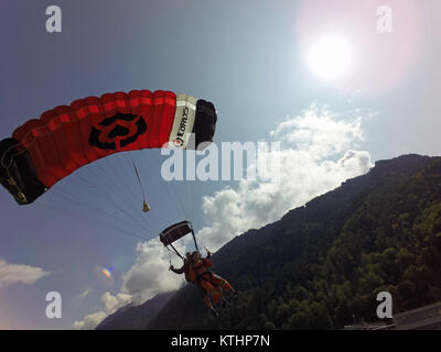 Tandem skydivers are flying under canopy and approaching the landing area. Soon they will touch down and be happy to be save back on the ground. Stock Photo