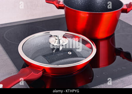 Frying pan and steel pot on modern induction cooktop. Stock Photo