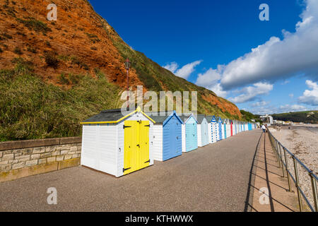 Colourful beach huts under the cliffs along the seafront promenade at Seaton, Devon, in the Jurassic Coast World Heritage Site, southwest England, UK Stock Photo