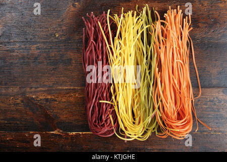 multicolored pasta on a wooden background, space for text Stock Photo