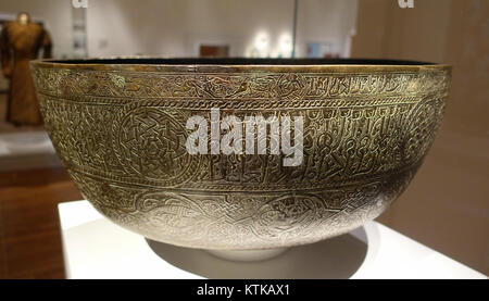 This 13th-century basin, believed to be from Iran, features engraved zodiac signs and a prayer. Made of cast white bronze, it is a significant example of Islamic art, housed in the Aga Khan Museum, Toronto. Stock Photo
