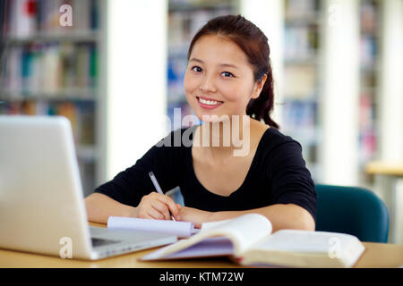 one young Chinese female univeristy student study in the library with laptop Stock Photo