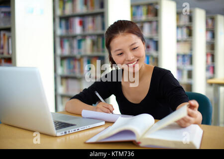 one young Chinese female univeristy student study in the library with laptop Stock Photo