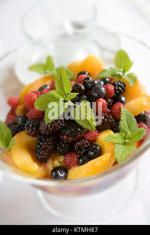 Fresh fruit salad with mint leaves in glass bowl Stock Photo