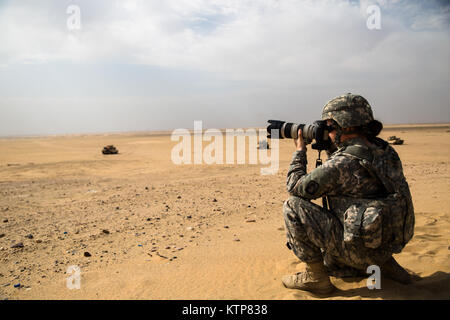 1st Lt. Emily McGuire, a Unit Public Affairs Representative with 3rd Battalion, 159th Attack Reconnaissance Battalion, 42nd Combat Aviation Brigade, takes a photo of a line of 4th Infantry Division tanks during a Joint Air Attack Team exercise with the 42nd Combat Aviation Brigade on May 21, 2014, near near Camp Buehring, Kuwait.  The 42nd CAB, comprised of Army National Guard units from New York, Michigan, and Delaware, and active duty units from the 12th CAB from Germany, is currently deployed to Kuwait and regularly conducts joint exchanges and exercises with forces across the region. (N.Y. Stock Photo