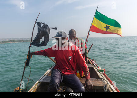 Fishermen in their open boat go fishing in the early morning. They paddle from net to net to fetch their catch, Kokrobite, Greater Accra Region, Ghana Stock Photo