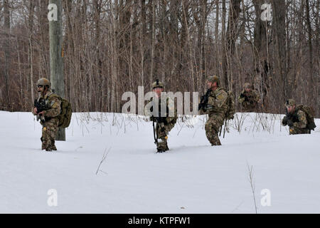 FORT DRUM, NY- Members of the 274th Air Support Operations Squadron (ASOS) move towards the objective training area during an exercise at Fort Drum, NY on March 14, 2015. Technical Sgt. David Santiago, left, Technical Sgt. Brandon Gilbert, Staff Sgt. Gerald Searfoss, Capt. Paul Spendley and Capt. Jeffrey Hansen trudge through snow during Close Air Support (CAS) training that enhances their ability to identify a target and neutralize a threat. 30 Airmen from the New York Air National Guard’s 274th Air Support Operations Squadron (ASOS), based at Hancock Field Air National Guard Base trained on  Stock Photo