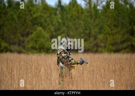 PERRY, GA - Technical Sergeant Carlos Morales, an Air National Guard Emergency Manager, searches for radioactive material during a Global Dragon training event at the Guardian Center of Georgia on March 15, 2015.    During this day's training, airmen searched for material following a simulated aircraft crash in a deployed location. Students wore Mission Oriented Protective Posture (MOPP) 4 gear, and used Gieger Counters to search through an empty field for the lost material.   Global Dragon provides a refresher course for Airmen, allowing them to put their skills to use to identify live chemic Stock Photo