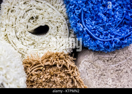 Closeup image of colorful fluffy home mats rolled for sale in supermarket Stock Photo