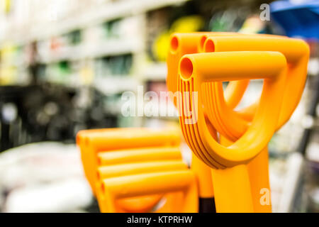 Close up plastic orange shovel handles in shop Stock Photo