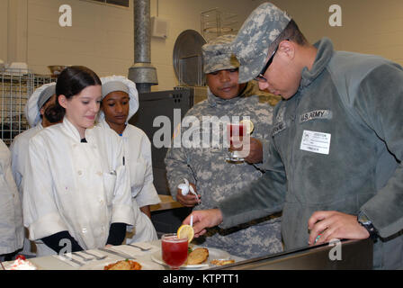 Student chefs (left) wait in anticipation as New York Army National Guard culinary specialists Sgt. Duwann Gordon (middle) and Pvt. Yorby Fernandez (right) judge a meal the students prepared using MRE food components at a Boards of Cooperative Educational Services (BOCES) vocational education facility in Goshen, N.Y. on Dec. 4, 2015. The students prepared meals with MREs as part of a New York Army National Guard educational challenge designed to test their skills and familiarize them with Army careers. The students chefs are, from left: Tyra Chase, a Middletown High School junior; Tushana Clar Stock Photo
