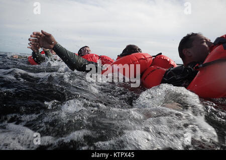 HOMESTEAD, FL - Members of the 101st Rescue Squadron conduct Water Survival Training (WST) near Homestead Air reserve Base on January 20, 2016. During this training, members train on the use of seven and twenty man survival rafts, the ability to work as a team in open water, and the use of their survival equipment. Additionally, aircrew members must conduct multiple dunks in the Shallow Water Egress Trainer in a four foot, man-made pool, and demonstrate an ability to exit an aircraft while upside down and completely submerged under water.   After conducting combat survival training in the subt Stock Photo