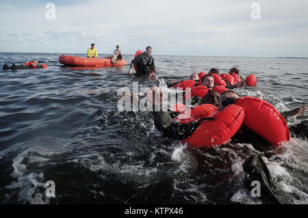 HOMESTEAD, FL - Members of the 101st Rescue Squadron conduct Water Survival Training (WST) near Homestead Air reserve Base on January 20, 2016. During this training, members train on the use of seven and twenty man survival rafts, the ability to work as a team in open water, and the use of their survival equipment. Additionally, aircrew members must conduct multiple dunks in the Shallow Water Egress Trainer in a four foot, man-made pool, and demonstrate an ability to exit an aircraft while upside down and completely submerged under water.   After conducting combat survival training in the subt Stock Photo