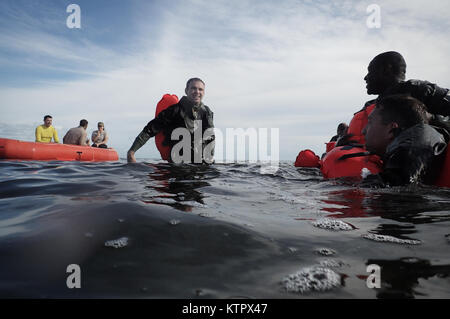 HOMESTEAD, FL - Members of the 101st Rescue Squadron conduct Water Survival Training (WST) near Homestead Air reserve Base on January 20, 2016. During this training, members train on the use of seven and twenty man survival rafts, the ability to work as a team in open water, and the use of their survival equipment. Additionally, aircrew members must conduct multiple dunks in the Shallow Water Egress Trainer in a four foot, man-made pool, and demonstrate an ability to exit an aircraft while upside down and completely submerged under water.   After conducting combat survival training in the subt Stock Photo