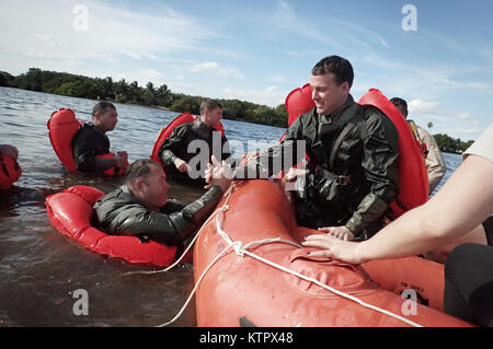 HOMESTEAD, FL - Major Dave Sumwalt pulls Captain Lonnie Mazuranich, both members of the 101st Rescue Squadron, aboard a survival raft during Water Survival Training (WST) near Homestead Air reserve Base on January 20, 2016. During this training, members train on the use of seven and twenty man survival rafts, the ability to work as a team in open water, and the use of their survival equipment. Additionally, aircrew members must conduct multiple dunks in the Shallow Water Egress Trainer in a four foot, man-made pool, and demonstrate an ability to exit an aircraft while upside down and completel Stock Photo