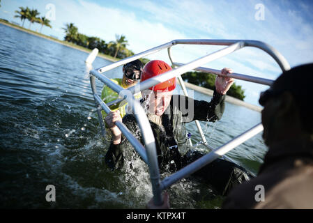 HOMESTEAD, FL - Members of the 101st Rescue Squadron conduct Water Survival Training (WST) near Homestead Air reserve Base on January 20, 2016. Aircrew members must conduct multiple dunks in the Shallow Water Egress Trainer in a four foot, man-made pool, and demonstrate an ability to exit an aircraft while upside down and completely submerged under water.   After conducting combat survival training in the subtropical Florida Everglades, aircrew must continue on to WST before completing their currency training.   (US Air National Guard / Staff Sgt. Christopher S Muncy / released) Stock Photo