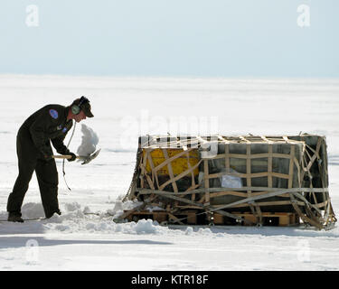 New York Air National Guard Staff Sgt. Matthew Jones, 109th Airlift Wing LC-130 &quot;Skibird&quot; Loadmaster clears snow from a pallet being uploaded onto a  LC-130 &quot;Skibird at Camp Raven, Greenland, on June 28, 2016.An LC-130 &quot;Skibird&quot; from the New York Air National Guard's 109th Airlift Wing in Scotia, New York, lands at Camp Raven, Greenland, near the DYE-2 site, on June 28, 2016. Crews with the 109th AW use Camp Raven as a training site for landing the ski-equipped LC-130s on snow and ice.  Four LC-130s and about 80 Airmen from the Wing recently completed the third rotatio Stock Photo