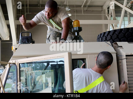 Pfc. Charles Liu, from the New York Army National Guard's 1st Brigade Combat Team, 69th Infantry Battalion, Headquarters Headquarters Company, and Spc Jason Sneed, also from the 1-69th, Delta Company, attach sensors for the Multiple Integrated Laser Engagement System  to an armored tactical vehicle at Fort Polk, La.   More than 3,000 New York Army National Guard Soldiers deployed to Fort Polk, Louisiana for a three week exercise at the Army’s Joint Readiness Training Center, July 9-30, 2016. Stock Photo