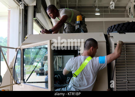 Pfc. Charles Liu, from the New York Army National Guard's 1st Brigade Combat Team, 69th Infantry Battalion, Headquarters Headquarters Company, and Spc Jason Sneed, also from the 1-69th, Delta Company, attach sensors for the Multiple Integrated Laser Engagement System  to an armored tactical vehicle at Fort Polk, La.   More than 3,000 New York Army National Guard Soldiers deployed to Fort Polk, Louisiana for a three week exercise at the Army’s Joint Readiness Training Center, July 9-30, 2016. Stock Photo