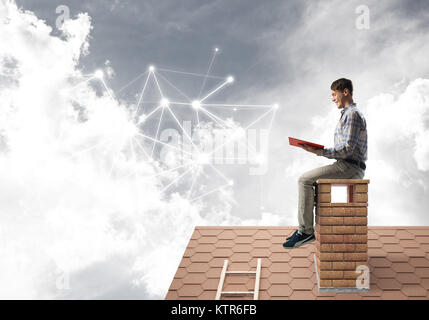 Man on brick roof reading book and concept of social connection Stock Photo