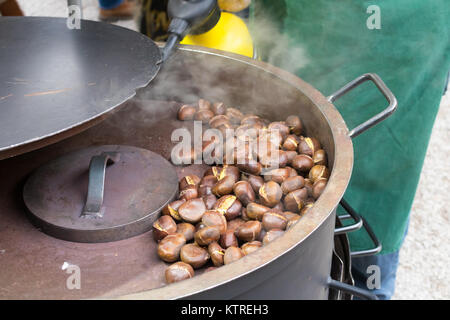 Street food market. Roasting brown chestnuts in a big pot.Winter Stock Photo