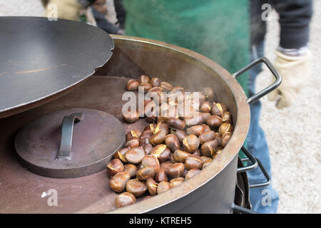 Street food market. Roasting brown chestnuts in a big pot.Winter Stock Photo