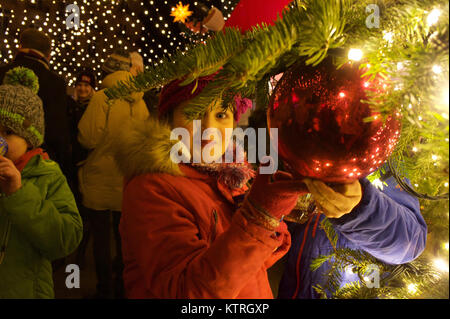 Portrait of a young german girl laughing with christmas ball in her hands at Cologne Cathedral Christmas Market. Stock Photo