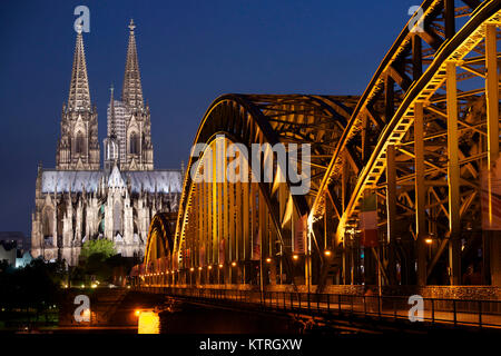 World heritage site Cologne Cathedral with Hohenzollern Bridge illuminated at night. At the famous cathedral is the shrine of the holy three kings. Stock Photo