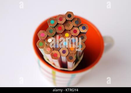 Wooden color pencils in orange cup isolated on white background Stock Photo