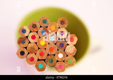 Wooden color pencils in green cup  isolated on white background Stock Photo