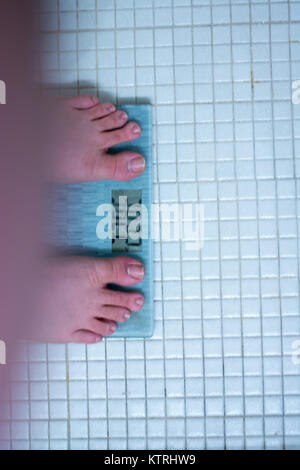 Obese man on bathroom scales planning on dieting for new years resolution. Stock Photo