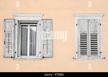 Two windows with window shutters in a beige house Stock Photo